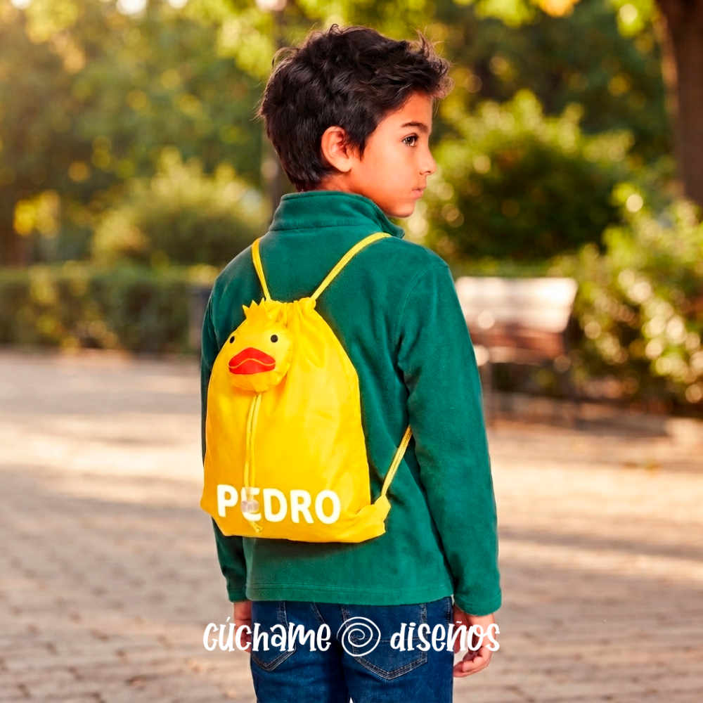 Niño llevando mochila de cuerdas amarilla con bolsillo de pato y nombre personalizado